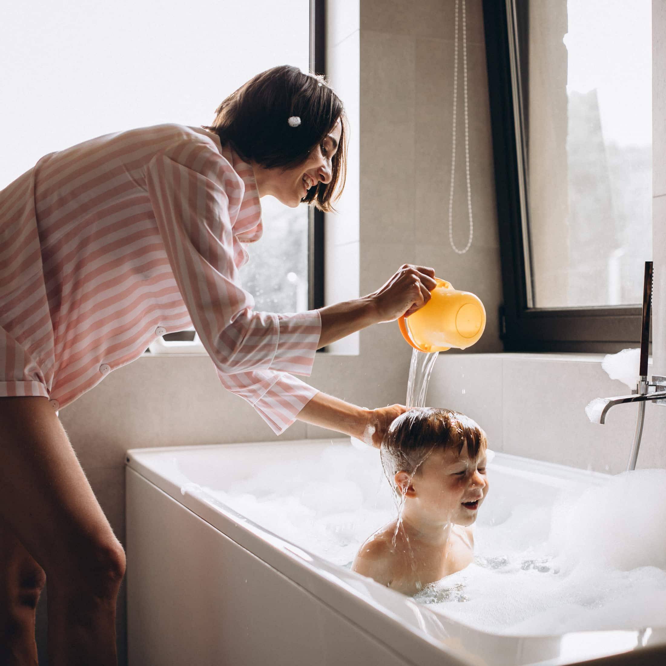 Mother washing little son in bathroom